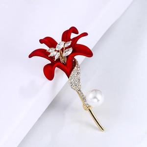 Close-up of red enamel lily brooch with sparkling rhinestones and white pearl detail