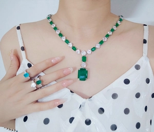 Close-up of luxury S925 silver necklace and ring set with emerald cut green gemstones