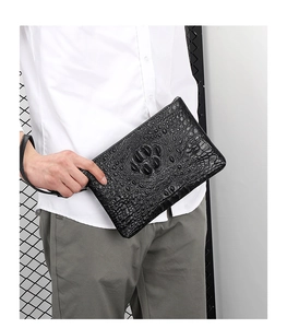 Detail of a black crocodile-patterned business clutch bag with wrist strap for men