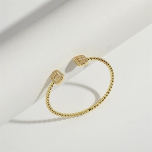 Detail of a luxury gold beaded open bracelet featuring elegant square-cut crystal accents