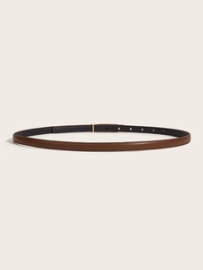 Close-up of minimalist slim leather belt with a polished metal buckle on beige background