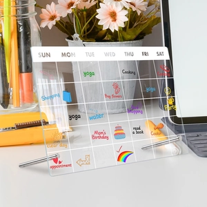 Clear acrylic weekly planner desk board with metal stands on an organized desktop