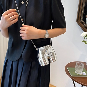 Futuristic silver metal hip-shaped mini crossbody bag with delicate chain strap on model