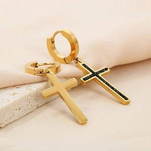 Golden cross drop earrings with black zircon inlay on textured stone background