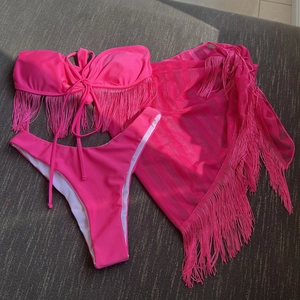 Close-up of three-piece rose pink bikini set featuring fringe details and mesh cover-up