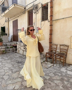 Detail view of light yellow ruffled long sleeve top and flowy maxi skirt set in elegant street style
