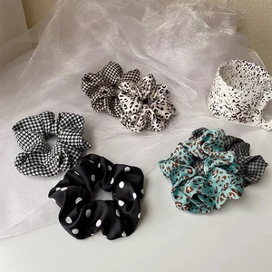 Detail of silk satin scrunchies featuring houndstooth, leopard, and polka dot patterns