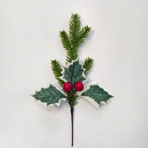 Detail of artificial Christmas pine branch with red berries and holly leaves on white base