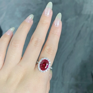Detail of an oval red ruby ring set in silver with small zircon accents on a model's hand