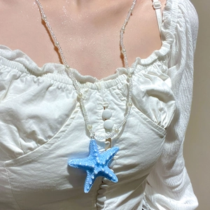 Detailed view of bohemian beach necklace with large blue starfish and white pearls