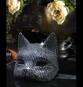 Close-up of a sparkling rhinestone cat-shaped masquerade mask on a luxury gold background