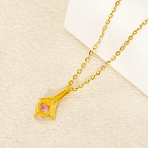 Elegant gold Eiffel Tower necklace with pink zircon stone on a white textured background