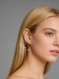 Detail of four different sized gold S925 sterling silver hoop earrings on a model ear