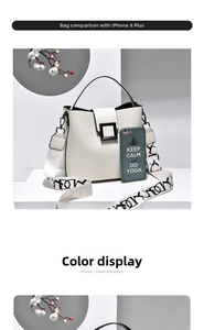 Detail shot of cream bucket bag with wide logo strap compared with a phone for size