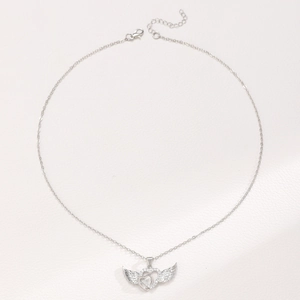 Detail of silver heart-shaped necklace with angel wings and sparkling crystal diamonds