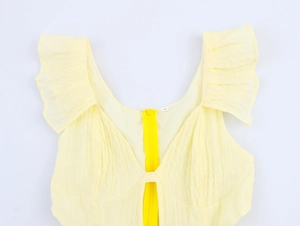 Detail of light yellow textured dress featuring V-neckline and ruffled flutter sleeves