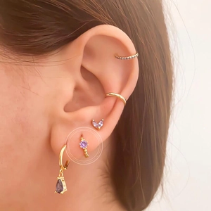 Close-up of C-shaped gold hoop earrings with purple zircon stone and matching ear cuffs