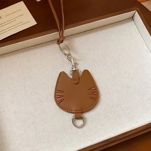 Brown PU leather cat-shaped pendant charm with silver metal clasp on a cream tray