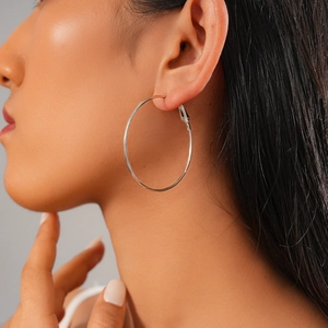 Close-up of a model wearing a large silver geometric round hoop earring in a minimalist style