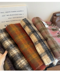 Detail shot of multi-color thick plaid scarves featuring soft fringe and knitted texture