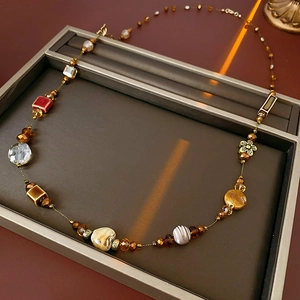 Détail des perles en céramique ambre et marron d'un collier vintage sur son présentoir