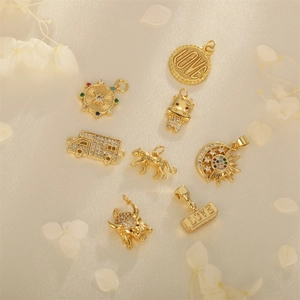 Set of eight gold-plated zircon charms including sunflower and coin shapes on beige fabric