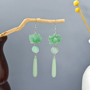 Macro detail of Chinese style lotus earrings with long pale green teardrop pendants