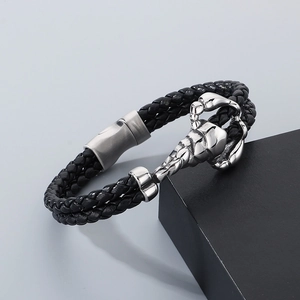 Detail of men's black braided leather bracelet with silver stainless steel scorpion motif