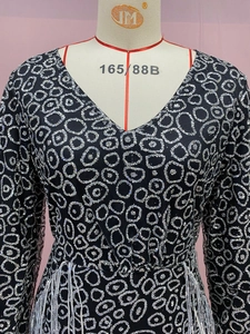 Detail of black long-sleeve dress featuring silver sequin circles and white fringe tassels