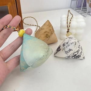 Detailed shot of three mini Zongzi charms with colorful cords and silk fabric textures