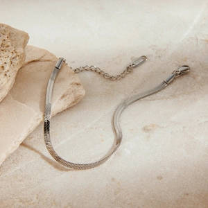Poliertes silbernes Schlangenketten-Armband aus Edelstahl auf Naturstein-Hintergrund