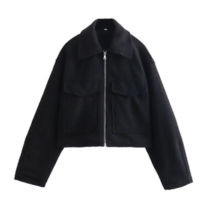 Détail d'une veste courte noire en bouclé avec fermeture éclair et doubles poches plaquées