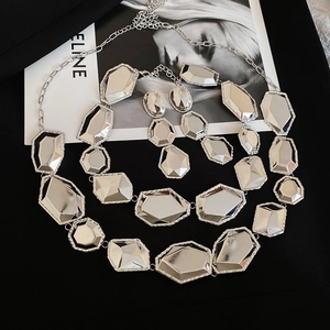 Détail de la parure collier et boucles d'oreilles géométriques argentées sur fond noir