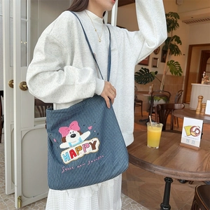 Close-up of cute cartoon puppy embroidery and HAPPY text on striped canvas tote bag