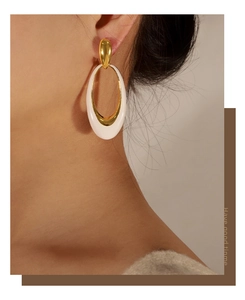 Macro detail of French vintage oval enamel earrings in gold and white on a model