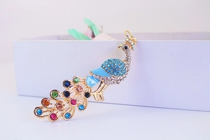 Macro detail of a colorful crystal peacock keychain with blue enamel and gold plating