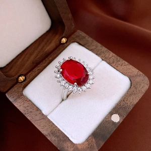 Detailed close-up of a vintage oval red gemstone ring in a wooden gift box