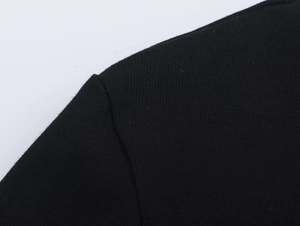 Detailed macro view showing the stitching and fabric texture of the black T-shirt shoulder