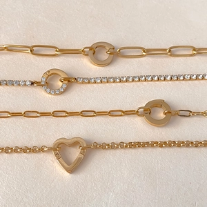 Detailed view of gold-plated bracelets featuring heart and circular clasps with crystals
