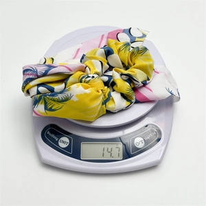Detailed view of floral scrunchie with ribbons weighing 14.7g on white scale