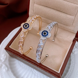 Detail of flower-shaped open bangles with blue center stones and cubic zirconia inlay