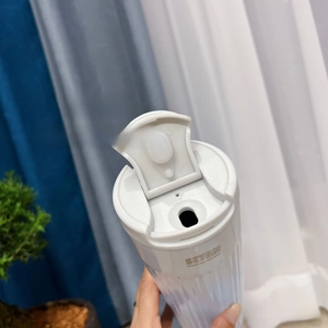 Detailed view of white stainless steel coffee tumbler with vertical textured stripes and flip lid