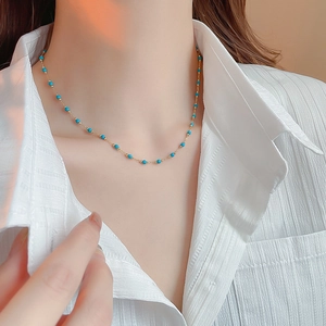 Detail of gold-plated bohemian necklace with blue beads on a model neck close-up