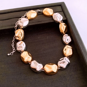 Detailed close-up of two-tone geometric metal bead chain with extender on black tray