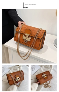 Close-up of brown crocodile texture flap bag with a jeweled metal bee clasp and chain