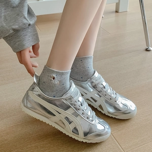 Metallic silver low-top sneakers in mirror leather on wooden floor with grey socks
