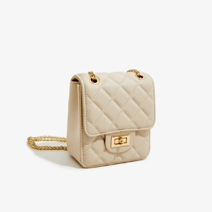 Side view of cream quilted crossbody bag with gold chain strap and turn-lock closure