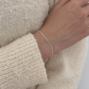 Detailed view of sterling silver star-shaped link bracelet on a cozy knit sweater
