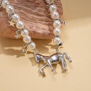Detail of faux pearl necklace featuring silver star charms and a polished horse pendant