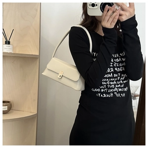 Chic white shoulder bag with metal buckle detail held by a model in a casual setting
